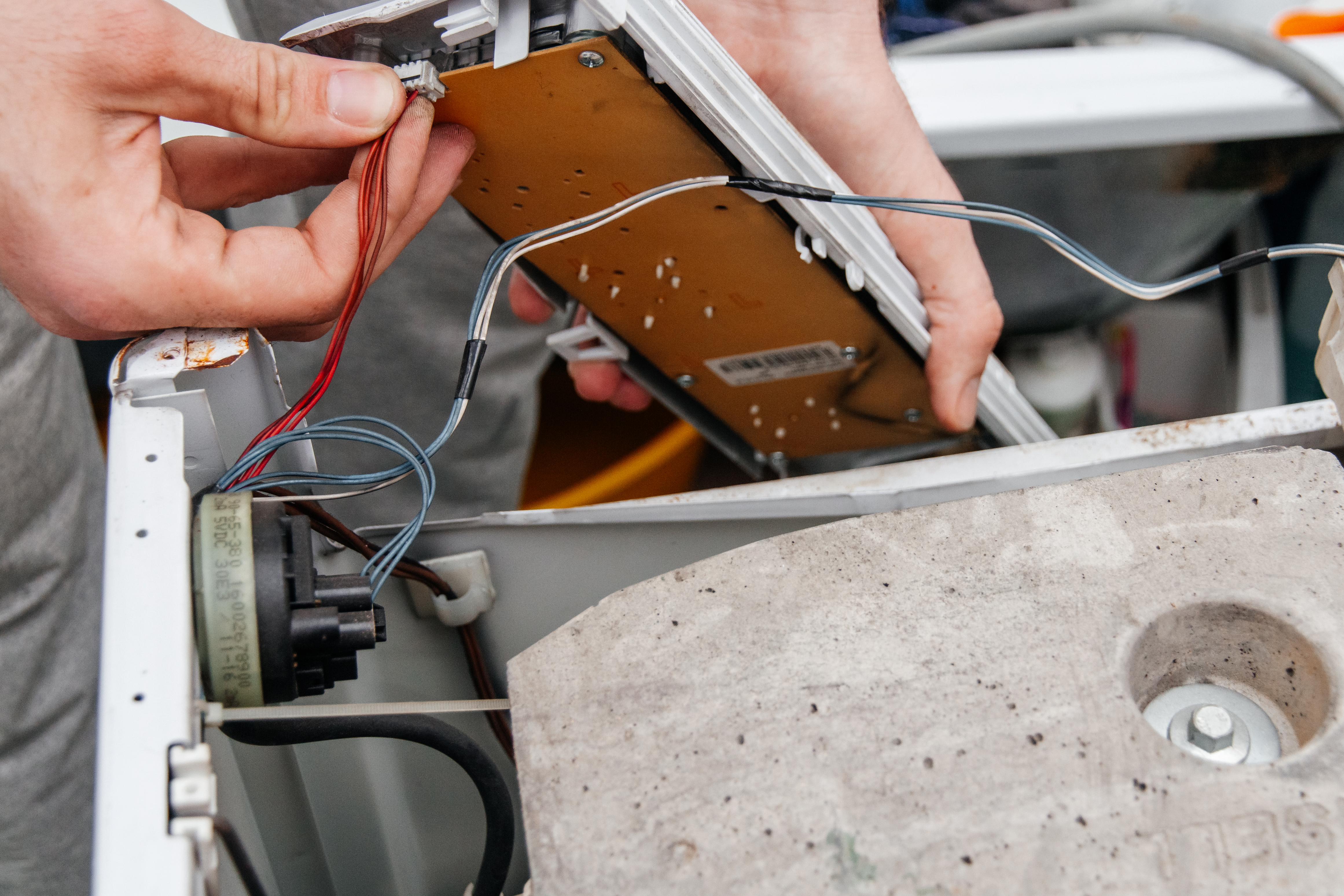 Handyman repairing a washing machine. The hands of a man repair a washing machine.