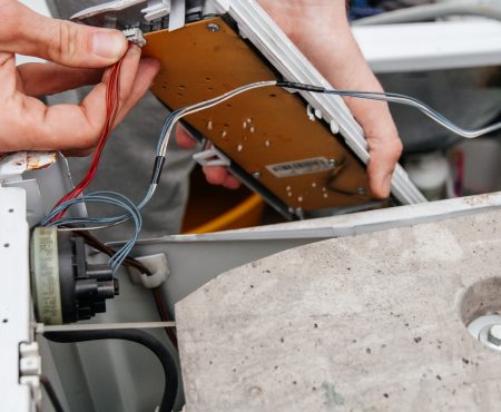 Handyman repairing a washing machine. The hands of a man repair a washing machine.